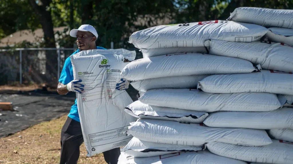 Worker stacking bags of landscape material outdoors